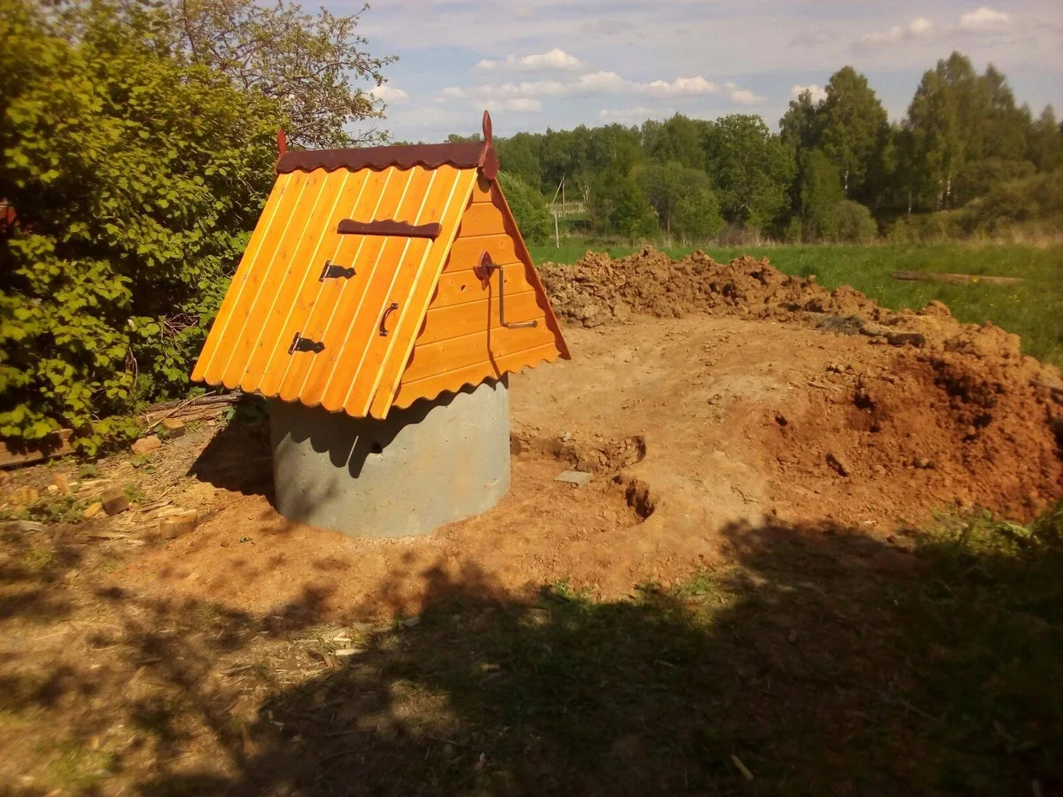 Готовый колодец с деревянным домиком в поле